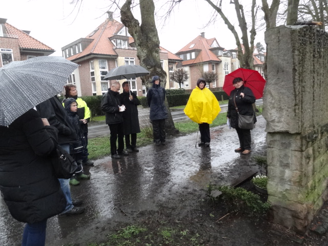 Marianne Feldmann (roter Schirm) von der Initiative Prozessionsweg erläutert die Kreuzwegsteine am Prozessionsweg