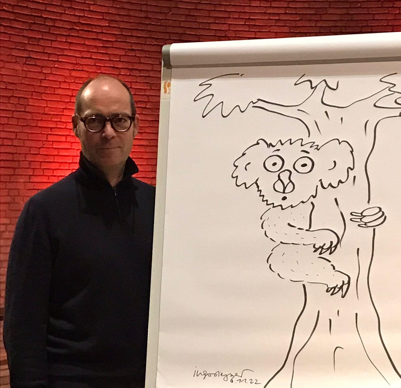Der Autor Ingo Siegner neben seiner Zeichnung. Foto: Anna Kopetsch