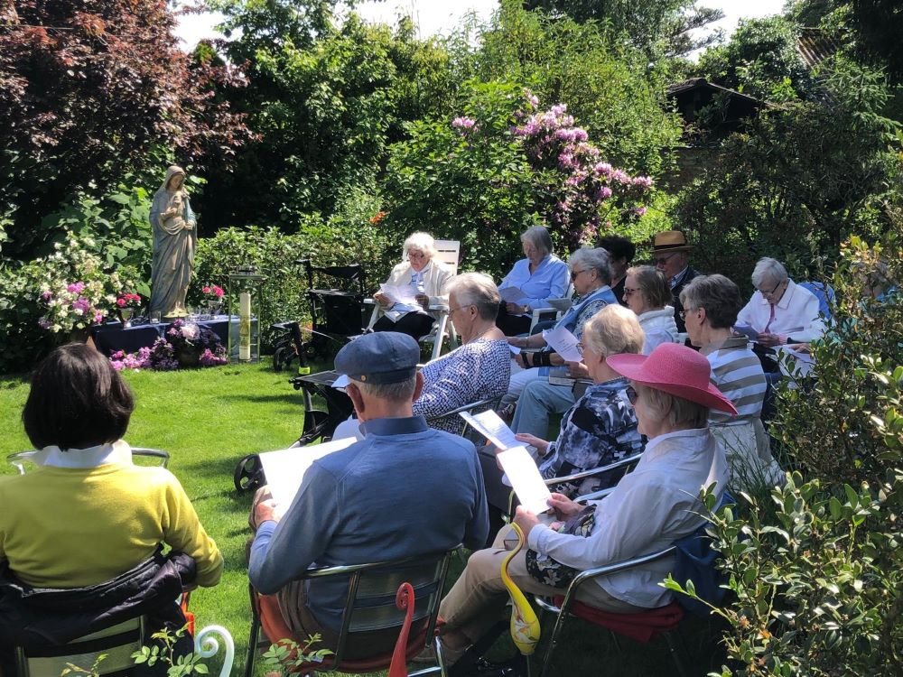 Teilnehmende im Garten bei der Andacht