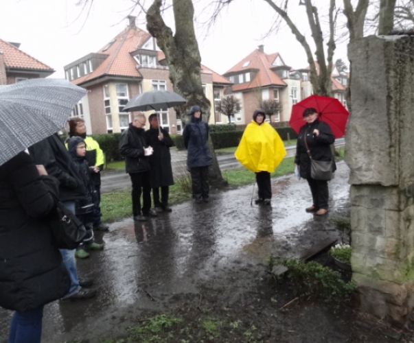 Marianne Feldmann (roter Schirm) von der Initiative Prozessionsweg erläutert die Kreuzwegsteine am Prozessionsweg