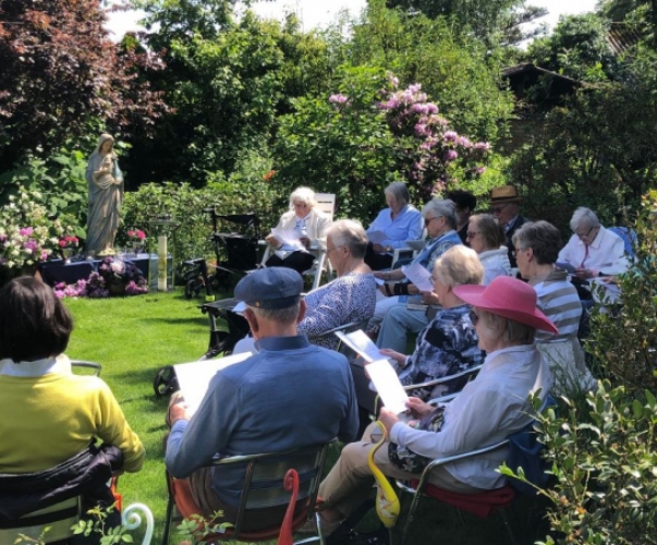 Teilnehmende im Garten bei der Andacht